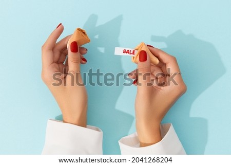 Creative composition for shopping sale. Women hands with manicure holding fortune cookie