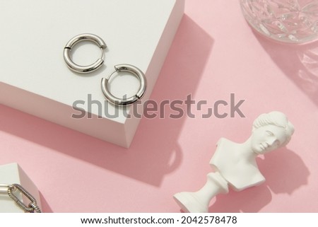 Creative composition with silver jewelry set on pink background. Trendy accessories in minimalist style