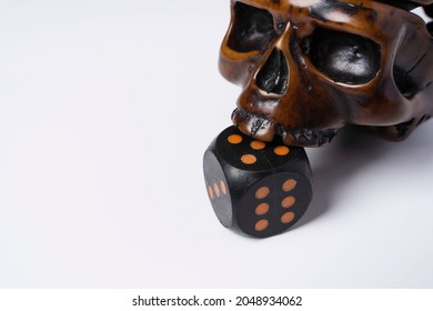 Creative composition of a skull and a dice, a skull bites a dice, on a white background, space for copying, Dramatic concept.