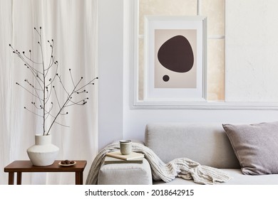 Creative composition of stylish and cozy living room interior with mock up poster frame, grey corner sofa, window, coffee table and personal accessories. Beige neutral colors. Template.