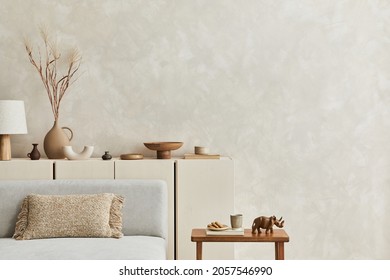 Creative composition of stylish living room interior with copy space, grey sofa, beige commode, clay vases and stylish personal accessories. Pastel neutral colours. Template.