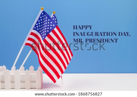 Creative composition with USA flags on white table with blue wall background, copyspace for text. Happy Inauguration Day wishes 2021 concept