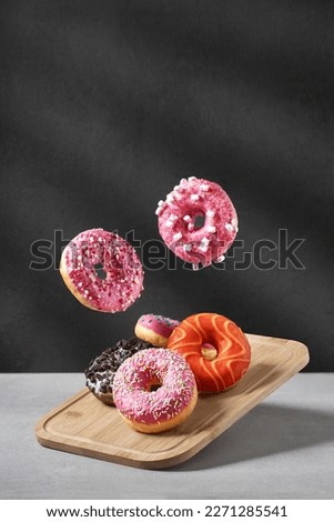 Creative composition of various donuts. A set of donuts with different color glaze on a wooden board. Donuts with chocolate, erysipelas icing, marshmallows and various flavorings.