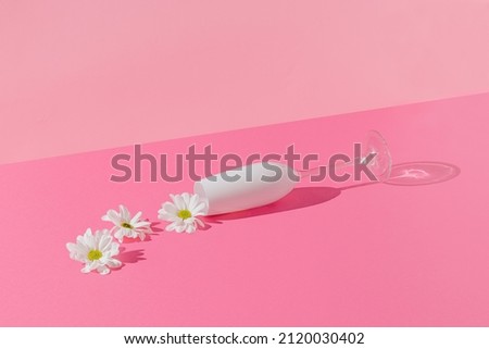 Creative composition with white flower spilling out of champagne glass on bright pink background. Minimal spring love or Mother's Day concept.