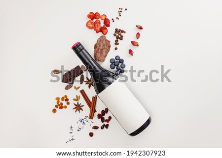 Creative composition with wine bottle and possible flavor components of red wine - berries, spices and other. Flat lay composition, wine tasting concept.