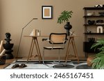 Creative composition of workplace interior with mock up poster frame, wooden desk, rattan chair, black rack, patterned rug, plant, brown wall, books and personal accessories. Home decor. Template.