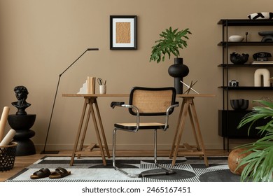 Creative composition of workplace interior with mock up poster frame, wooden desk, rattan chair, black rack, patterned rug, plant, brown wall, books and personal accessories. Home decor. Template.