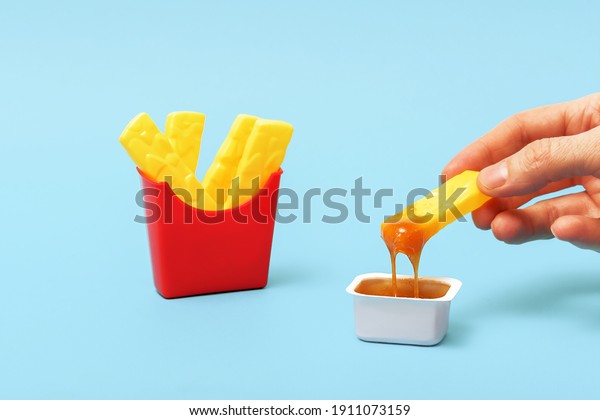 Creative concept of junk food. Fake fries are dipped\
in sauce.   \
\
