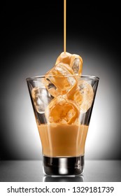 Creative Concept Photo Of Alcohol Spirits Drink Beverage Cocktail Irish Cream Liqueur Pouring Into A Glass Full Of Ice