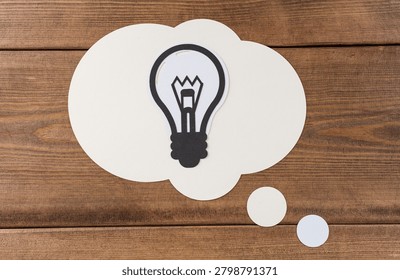 Creative concept represented by lightbulb thought bubble on wood