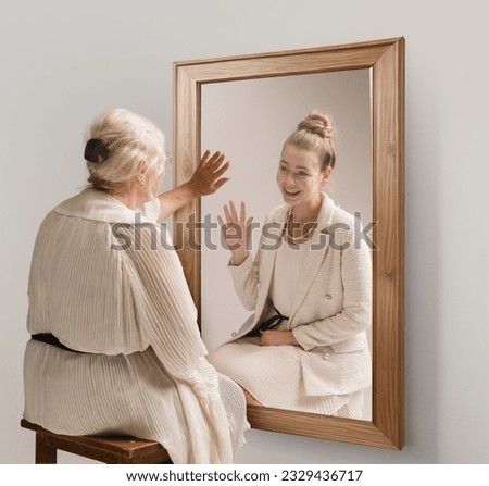 Creative conceptual collage. Tender image of senior woman looking in mirror and smiling to her young self reflection. Back to past. Concept of present, past and future, age, lifestyle, memories, ad