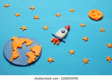 Creative craft plasticine rocket in open space, astronaut dreams. Stars, planet earth and moon. Cartoon art.