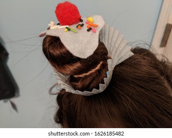 Creative, Crazy Frosted Cupcake Bun Hairstyle With Sprinkles And A Red Cherry Pom-pom On White Feel With A Cupcake Wrapper For Wacky Hair Day