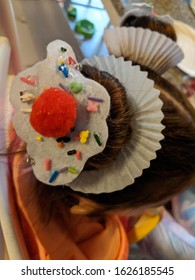 Creative, Crazy Frosted Cupcake Bun Hairstyle With Sprinkles And A Red Cherry Pom-pom On White Feel With A Cupcake Wrapper For Wacky Hair Day