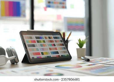 Creative designer, Graphic at workspace with digital tablet, color swatch samples and stationery on wooden table - Powered by Shutterstock