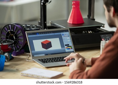 Creative designer working over new 3d model on laptop screen before printing it on special equipment in office - Powered by Shutterstock