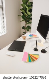 Creative designer workplace with desktop computer, stylus and tablet.