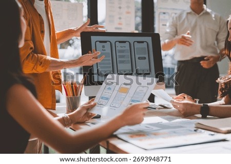 Creative designers and developers discussing mobile application wireframes, planning the strategic user interface and experience