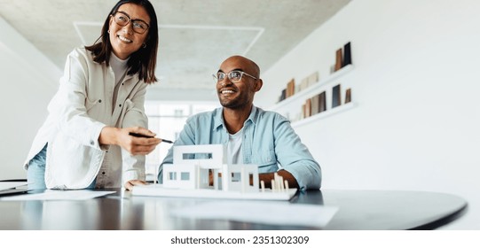 Creative designers working on a 3D house model in an office. Young business people planning a new architectural project. - Powered by Shutterstock