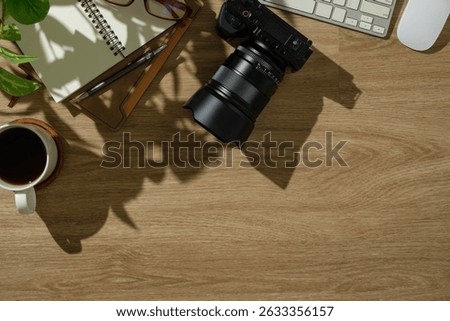 Photographer’s creative desk setup with camera gear, planner, coffee, and natural plant shadows.