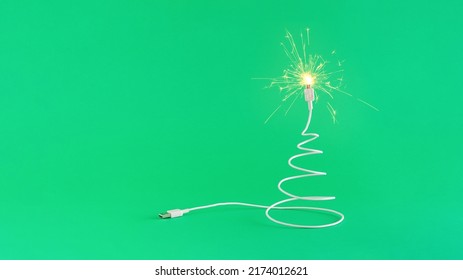 Creative digital technology Christmas arrangement made of USB cable in the shape of a Christmas tree and sparkles on a green background. Minimal New Year concept with copy space. Online holiday insp - Powered by Shutterstock