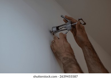 Creative DIY life hack using a corkscrew to remove a wall plug. Man using unconventional household tool for home repair. Innovative solution, budget fix, handyman tip