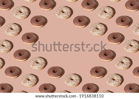 Creative doughnut layout pattern on pastel beige background with copy space.  Chocolate donuts pattern. Brown colour mood. Unhealty and tasty meal. Flat lay.