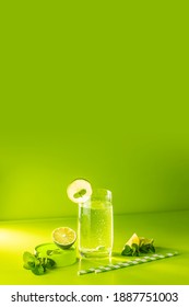 Creative drink background. Fresh Mojito cocktail with lime and mint in highball glass with water drops on green background in bright light, Mojito refreshing drinks. Summer vacation and party concept