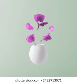 Creative Easter concept. White egg with purple flowers on blue pastel background. 