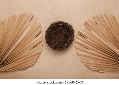 Creative easter layout. Empty nest and dry palm leaves on beige background. Flat lay