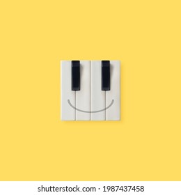 Creative emoticon made of piano keys isolated on illuminating yellow background. Aesthetic, abstract, positive emotion music concept. Happy face emoji idea. Minimal flat lay. 