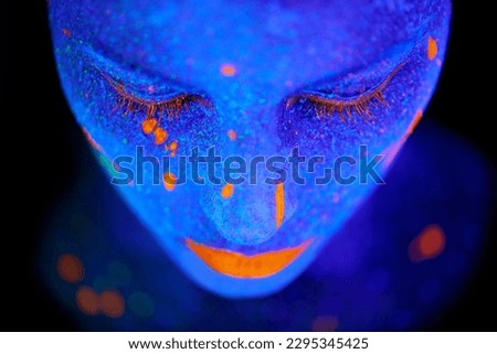 Creative, face and woman with neon paint in studio for fantasy, art or psychedelic aesthetic. Illusion, creativity and female model with glitter and bright color facial cosmetics by black background.