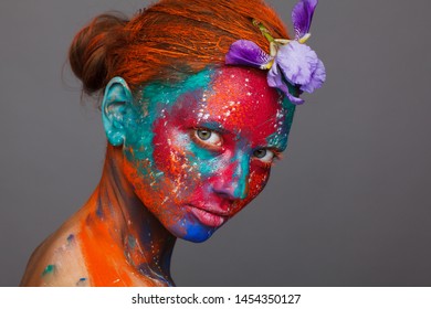 Creative fantastic makeup using colorful paints on the model. Studio beauty photoshoot