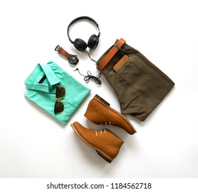 Creative Fashion Design For Men Casual Clothing Set With Ankle Boot , Watch, Sunglasses, Trousers, Earphone, Shirt And Wallet Isolate On White Background, Top View. Pack Shot