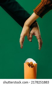 Creative Fast Food Concept. Close-up, Hands Reaching For A Box Of Nuggets. Studio Photo On A Green Background.