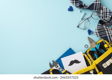A creative Father's day setup with various tools in a yellow bag, stylish tie, glasses, and heart shapes on a soft blue background
