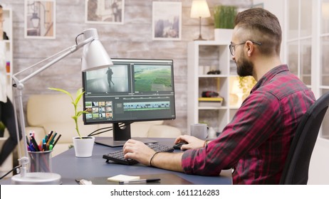 Creative Filmmaker Working On Post Production Of A Movie While Working From Home. Girlfriend In The Background Is Walking In The House And Talking On The Phone.