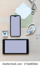 Creative flat lay. Alternative wedding invitation with blank screens of phone and tablet for text and photos. Custom card to announce celebration. Romantic and cute template with engagement rings.