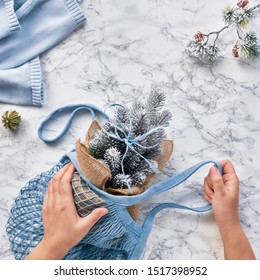 Creative Flat Lay With Artificial Plastic Christmas Tree In Mint Blue Eco Friendly Mesh Bag. Real Or Fake Xmas Tree Dilemma For Conscious Lifestyle People. Flat Lay On Marble, Square Composition