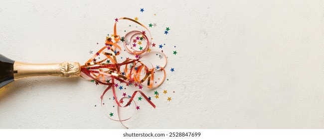 Creative flat lay composition with bottle of champagne and space for text on color background. Champagne bottle with colorful party streamers. holiday or christmas concept.