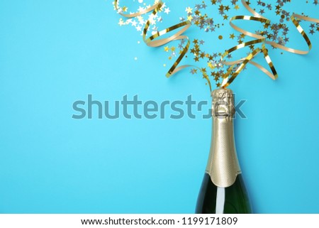 Creative flat lay composition with bottle of champagne and space for text on color background