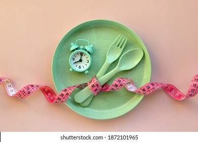 Creative flat lay composition with plate, alarm clock, spoon, fork and measuring tape on pink background. Intermittent fasting, ketogenic, diet concept.  Flat lay, copy space.
 - Shutterstock ID 1872101965