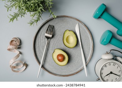 Creative flat lay composition with plate, alarm clock, knife, fork, dumbbell and measuring tape on gray background. Intermittent fasting, ketogenic, diet concept. top view, copy space.