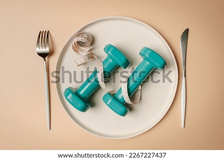 Creative flat lay composition with plate, fork, knife, dumbbell and measuring tape on pink background. Intermittent fasting, ketogenic, diet concept. top view, copy space.