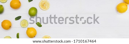 Creative flat lay composition with yellow lemons sliced and halved with mintleaves a white wooden background. Banner format with copy space