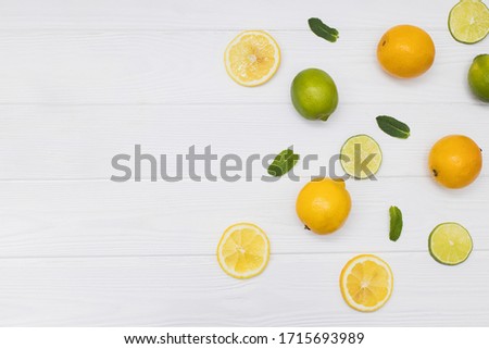 Creative flat lay composition with yellow lemons sliced and halved with mintleaves a white wooden background