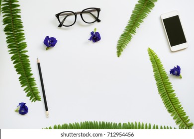 Creative Flat lay design of blank notebook, smartphone,glasses and pincil with green leaf on white background.