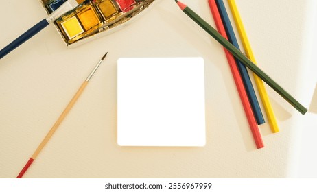 A creative flat lay featuring an artistic workspace. The composition includes a watercolor palette with vibrant paints, a fine paintbrush, and colored pencils in green, red, blue, and yellow, arranged - Powered by Shutterstock