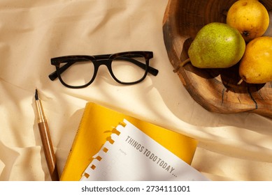 Creative flat lay of fresh pears, planner page, pen and glasses, illuminated by soft natural light