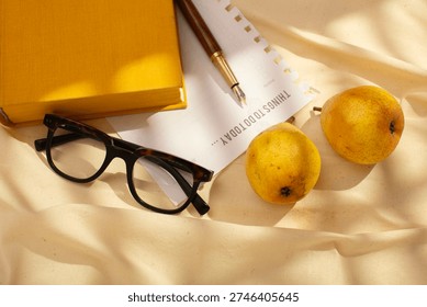 Creative flat lay of fresh pears, planner page, pen and glasses, illuminated by soft natural light
